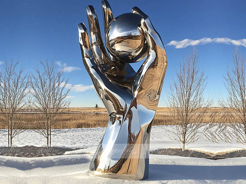 metal hand and ball sculpture