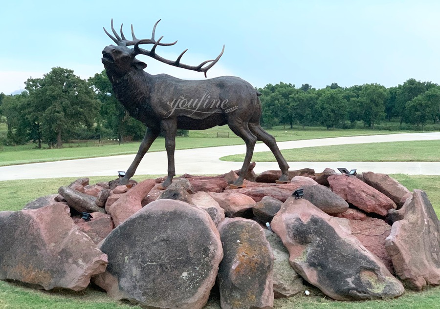 large elk bronze statue on rock