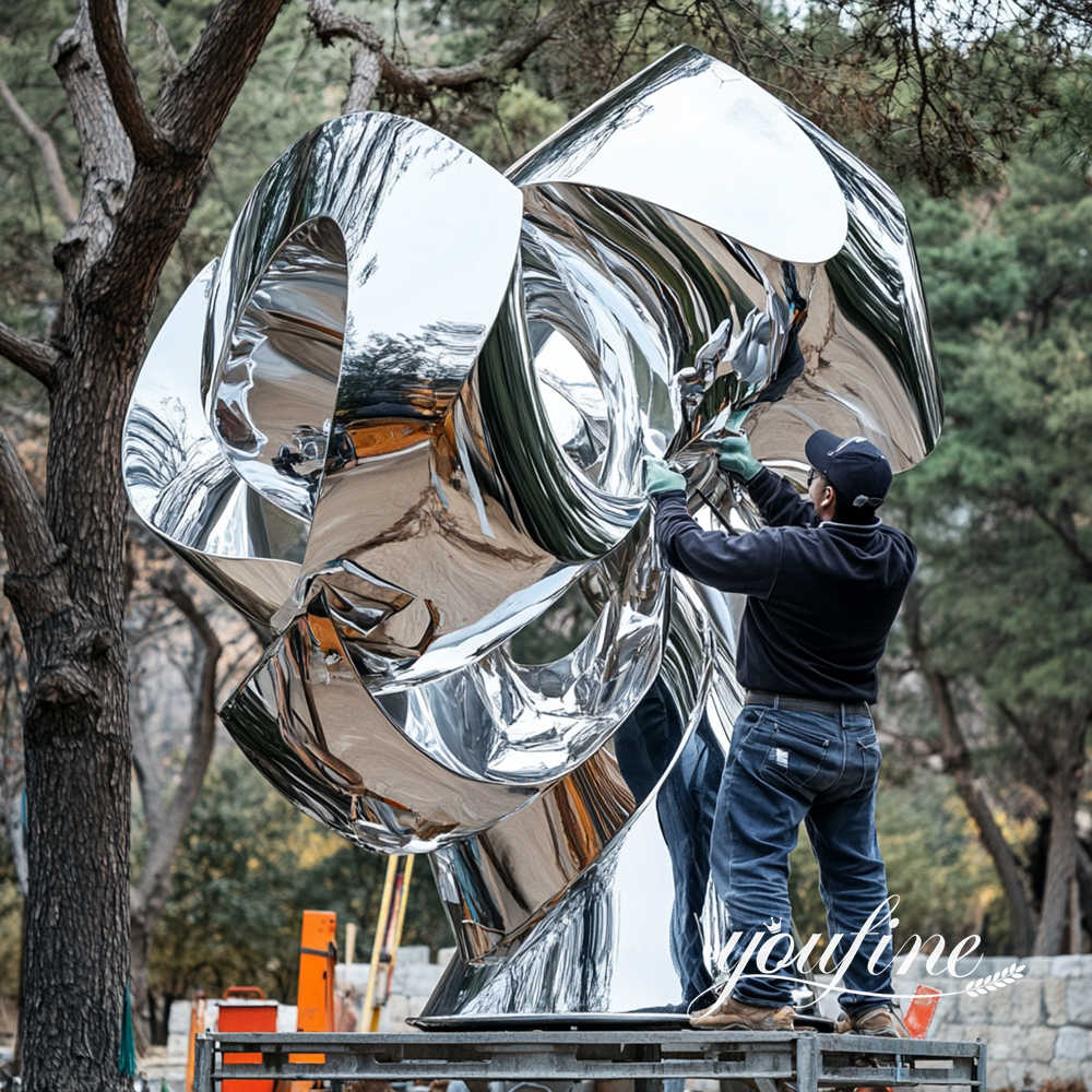 professional staff maintaining large nirror polished stainless steel sculpture