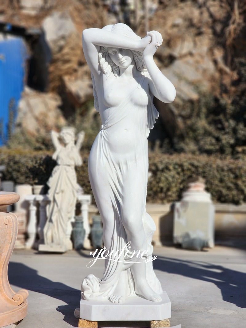 White marble sculpture of a standing woman with raised arms and flowing drapery
