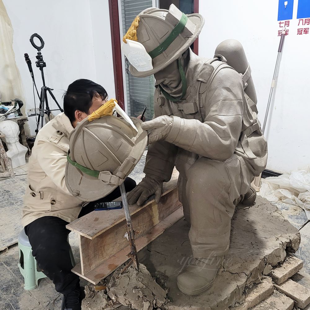 Tonmodell einer Gedenkstatue eines knienden Feuerwehrmanns mit Helm