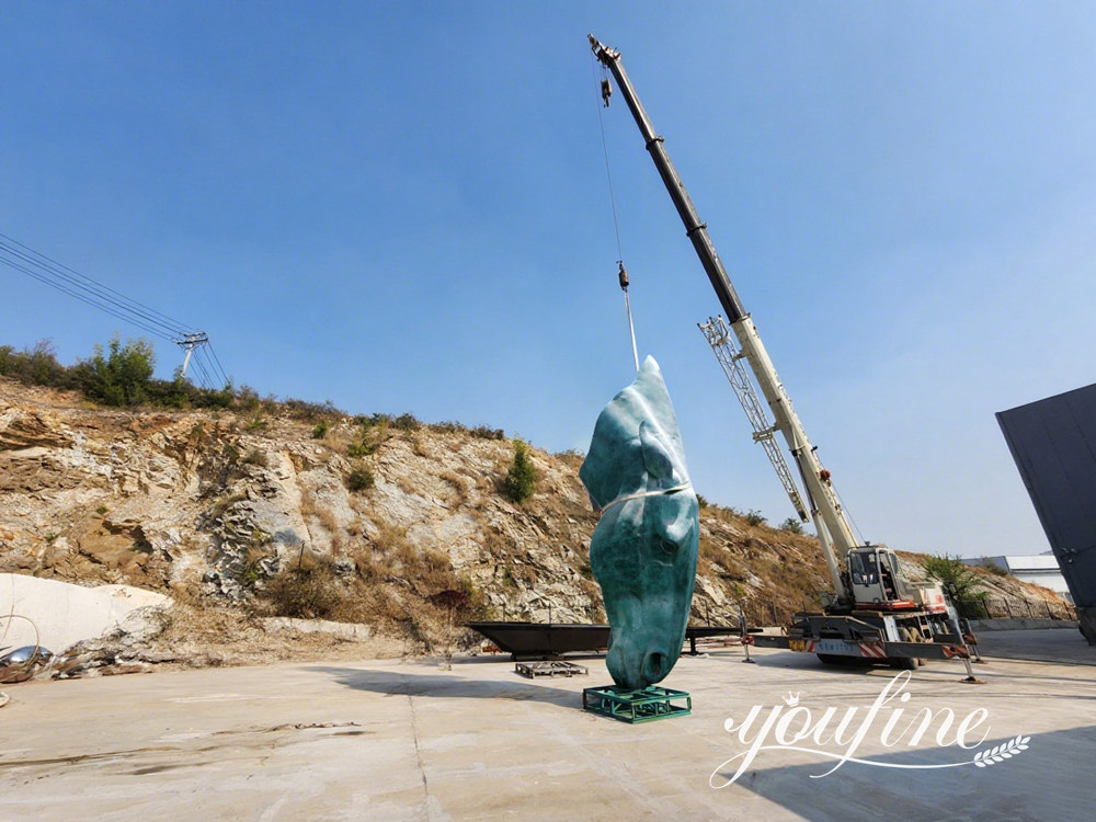 Große grüne Bronze-Pferdekopfskulptur, die von einem Kran getragen wird bei YouFine Fabrik